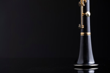 A bell of a clarinet on a reflective surface with a dark background