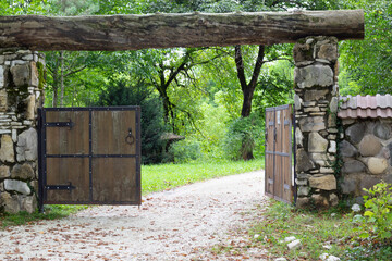 The wooden gate in a stone wall on a monastery. Retro countryside wooden gate with with stone wall in vintage style. Peaceful nature. Conceptual image.