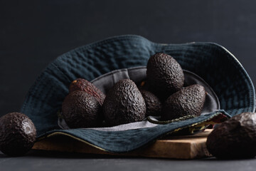 Avocado fruit in green cloth hat on black background, diet eating food for good health