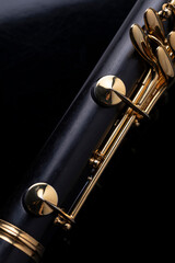 Naklejka premium Part of a clarinet with gold plated keys on a black background. A woodwind instrument common to classical music.
