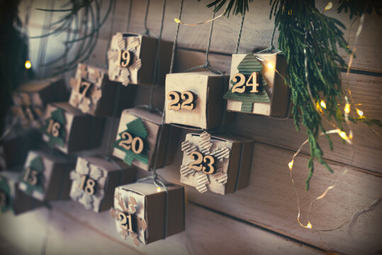 Homemade small carton boxes for advent surbrises with fairy light. Hanging vintage advent calendar made of cardboard for a environmentally conscious christmas. Close-up with short depth of field.