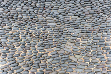 Pavement with round black boulders. Paved surface with round black pebbles. Traditional pavement on sidewalks and squares with black lava stones in Lanzarote, Canary Islands, Spain