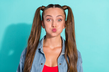 Photo of funny childish young woman dressed denim jacket ponytails bloated cheeks isolated teal...