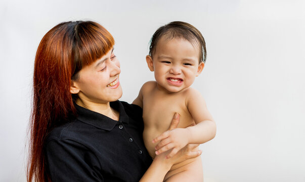 Happy mother with her baby on isolated white background. Mom wearing black shirt holding her son and smiling merrily. Young attractive happy mother smiling hugging looking at her little baby.