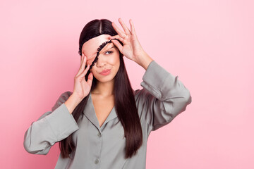 Portrait of attractive irritated girl touching blindfold waking up early time isolated over pink...
