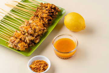 Sate taichan or Taichan satay with grilled chicken skin  is a variation of chicken satay grilled and served without peanut or ketchup served with chili sauce. Selective focus , blurry. 
