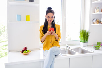 Photo of pretty cute dark skin woman dressed yellow shirt sitting table typing modern device indoors house home room