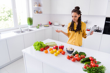 Photo of doubtful charming dark skin woman dressed yellow shirt deciding what cooking indoors house home room