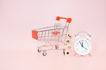 stack of contact us icon on wood cubes, white analog alarm clock and blurred shopping cart on sweet pink background for online shopping, nonstop service, contact us concept