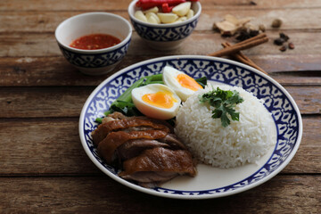 Local Thai food stewed pork leg on rice isolated in wood background