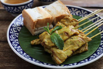 Local Thai food pork satay with oeanut dipping sauce isolated in wood background