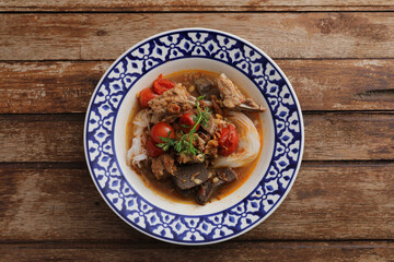 Local northern thai food Rice noodles with pork in spicy soup in wood background
