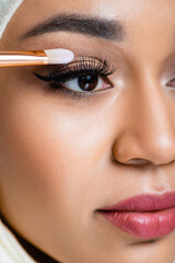 Naklejka premium close up of muslim woman applying eye shadow with cosmetic brush