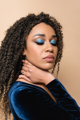 curly african american woman with bright makeup posing isolated on beige