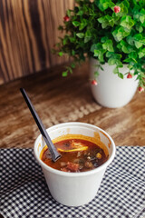 Close-up of a hodgepodge in a disposable paper cup. The concept of traditional food and foreign cuisine. Safe eco-friendly disposable tableware.