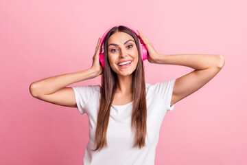 Photo of impressed young brunette lady listen music wear white t-shirt isolated on pink color background