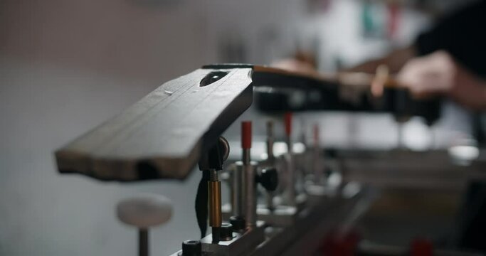 Luthier mounts the electric guitar on the jig at the musical instruments repairing shop, 4k 60p 10 bit