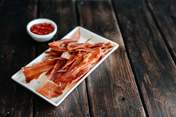Dried chicken cut into strips on a wooden board with salt, pepper, adjiga, ketchup. High quality photo