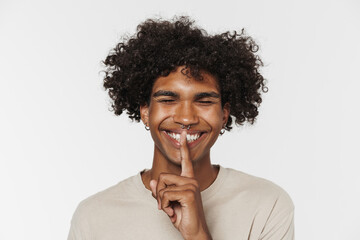 Young black man with piercing smiling while showing silence gesture