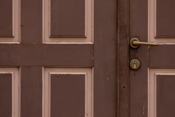 A vintage brown wood door with tile features and a door knob