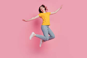 Photo of inspired funny brunette woman jump fly pretend plane wear casual jeans clothes on pink...
