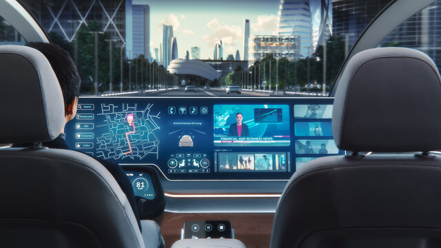 Futuristic Concept: Stylish Businessman Using Navigation App on an Augmented Reality Dashboard with Financial News Broadcast while Sitting in an Autonomous Self-Driving Zero-Emissions Electric Car. 