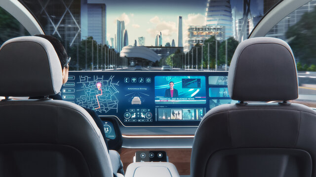 Futuristic Concept: Stylish Businessman Using Navigation App on an Augmented Reality Dashboard with Financial News Broadcast while Sitting in an Autonomous Self-Driving Zero-Emissions Electric Car. 