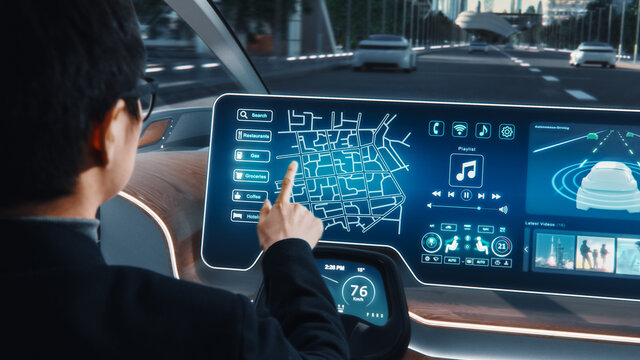 Futuristic Concept: Stylish Businessman Setting Location on an Interactive Navigation App on an Augmented Reality Dashboard while Sitting in an Autonomous Self-Driving Zero-Emissions Electric Car. 