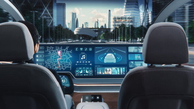 Futuristic Concept: Stylish Businessman Using Navigation App on an Augmented Reality Dashboard with Financial News Broadcast while Sitting in an Autonomous Self-Driving Zero-Emissions Electric Car. 