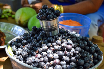 Stock photo of fresh organic black current barriers kept in bowl and steel glass for at local street market in Indian village. Picture capture during summer season. selective focus. blur background.