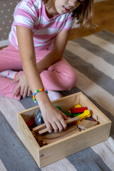 Child takes out wooden toys from the box. Railway toy. Montessori material. Home schooling concept.
