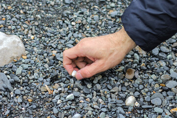 Man hand picking up stones from the river beach