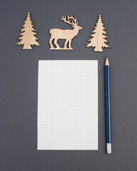 Empty piece of paper with a pen, christmas season, reindeer and wooden trees, wishing list for...