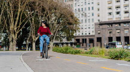 young latina business woman riding her bicycle on the bike path smiling