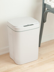 Smart recycle bin. Electronic gadget for home and office. Stands on a wooden floor. Next to the...