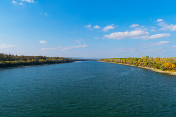 Beautiful autumn scenery. The blue Danube and the forest in the colors of autumn.