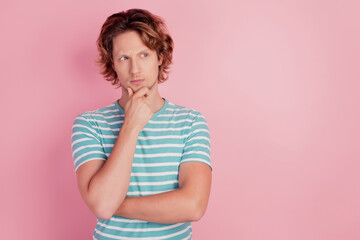 Photo of minded thoughtful smart man finger chin look empty space wear casual blue striped t-shirt on pink background