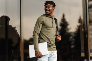 American man, wearing glasses, businessman walking on stairs and holding laptop computer while...