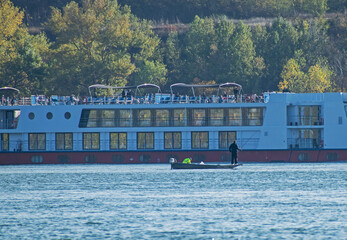 Fototapeta na wymiar Cruise ship on the Danube. The cruise ship passes the fisherman's boat.
