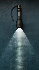 Tactical flashlight shines with bright beam on grunge dark blue background