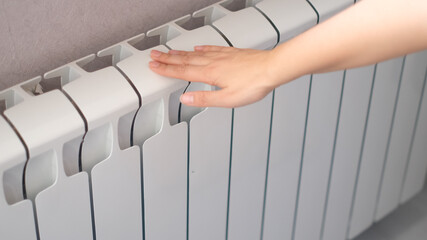 woman's hand touches the radiator. hot radiator, heating season concept
