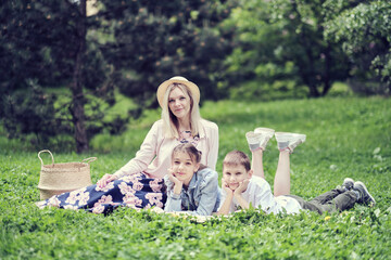 family spends the weekend in nature. happy family outdoors on the grass in a park. Mother Carrying Son And Daughter As They Play In Park. soft focus