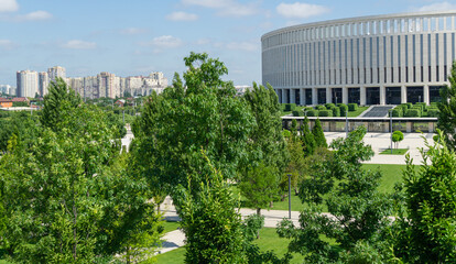 Landscape with beautiful ornamental trees and white facade stadion. Public landscaped city park 'Krasnodar' or 'Galitsky park'. Best place for relaxation and walking.