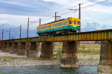 北アルプスを背景に、常願寺川橋梁を渡る富山地方鉄道本線の電車