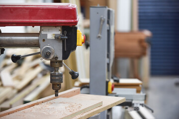 Drill machine for drilling wood in a carpentry workshop
