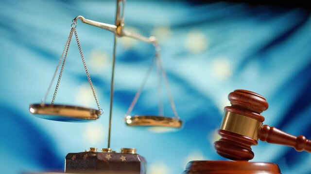 A judge gavel with a flag of European Union on background. Close up of wooden hammer and legal lawyer books or codex. Sentence law or legal system and jurisprudence or court concept.