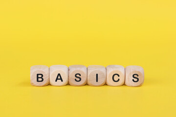 Wooden cube with the text BASICS on  yellow background. Basic business concepts or simplification studies