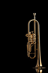 Fototapeta na wymiar A gold plated rotary trumpet on a reflective surface. A brass instrument common in classical music.