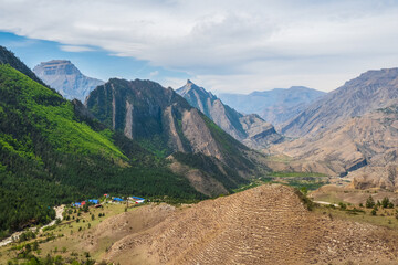 Picturesque mountain valley in Dagestan. Colorful sunny green landscape with river and silhouettes of big rocky mountains and epic deep gorge.