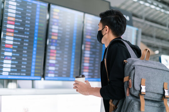 Asian Male Wearing Face Mask Traveler Giving Boarding Pass And Passport To Customer Check In Officer At Service Counter Airport.Man Wearing Face Mask When Traveling To Prevent Coronavirus Pandemic.
